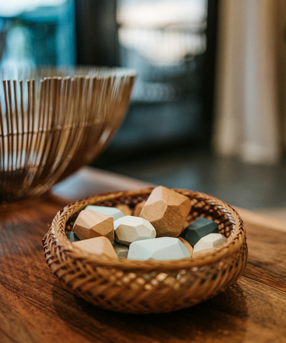 Piedras de madera lisas en un cuenco tejido sobre una mesa